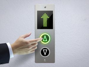 Hand of a man pressing the elevator button for next levels up in concept of more advance to a success.
